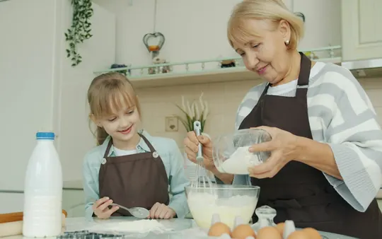 Een oma en haar kleindochter bakken samen in de keuken